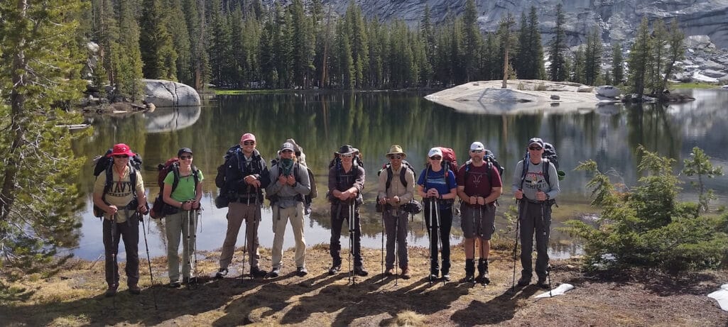 A group of backpackers in front of an alpine lake