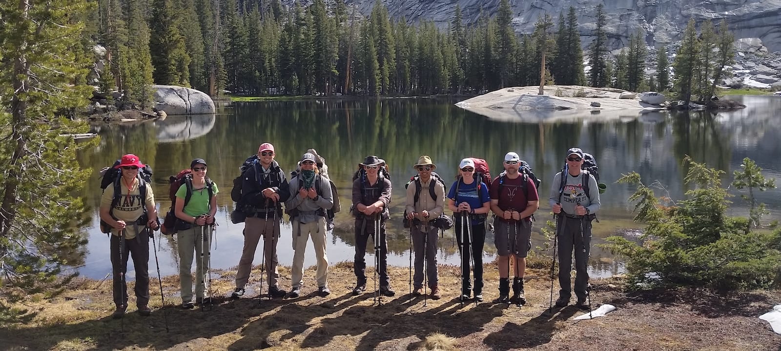 A group of backpackers in front of an alpine lake