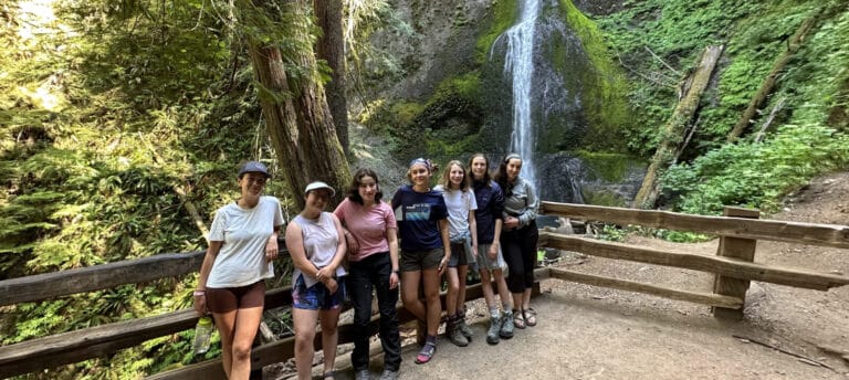 A group of young women enjoy the views of a local waterfall in Olympic National Park.