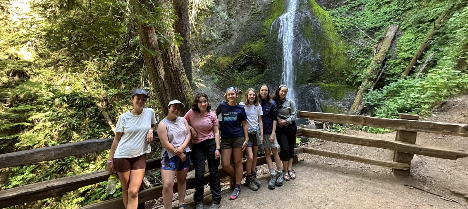 A group of young women enjoy the views of a local waterfall in Olympic National Park.