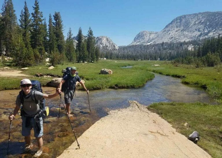 wading a river on a yosemite backpacking adventure