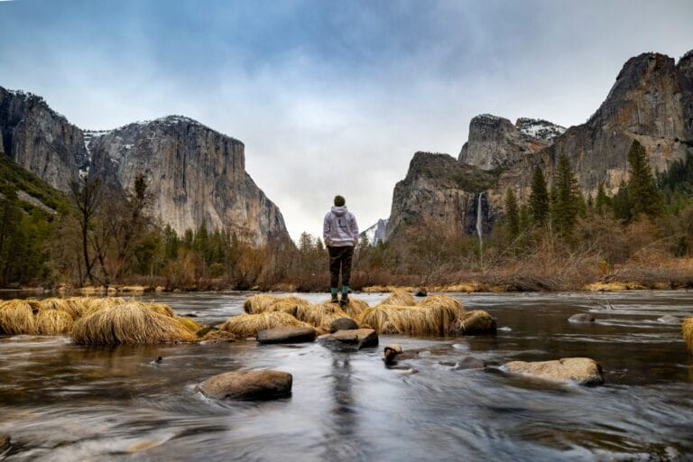 Hiker enjoys winter Valley View next to the Merced River in Yosemite Valley.