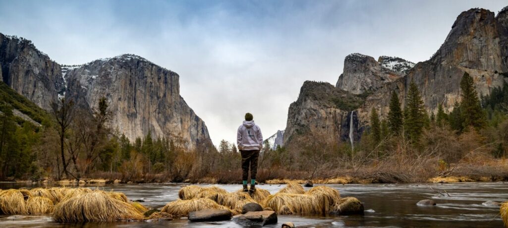 Hiker enjoys winter Valley View next to the Merced River in Yosemite Valley.