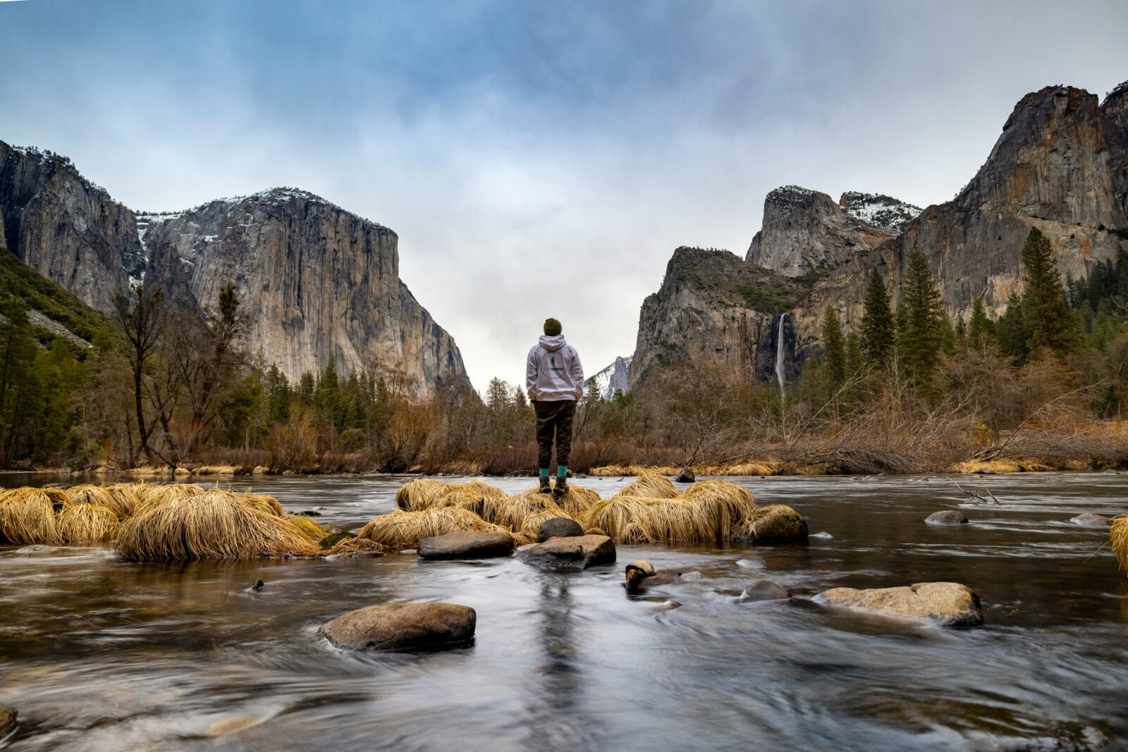 Hiker enjoys winter Valley View next to the Merced River in Yosemite Valley.