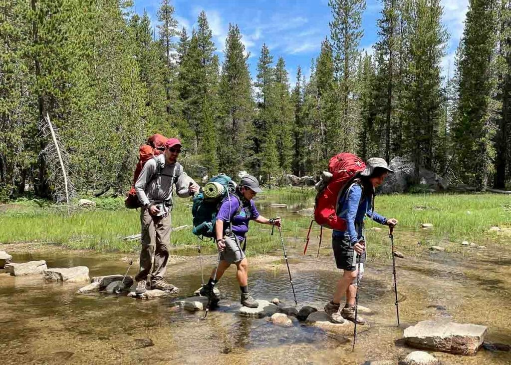 walking across the creek on one of our guided Yosemite backpacking trips