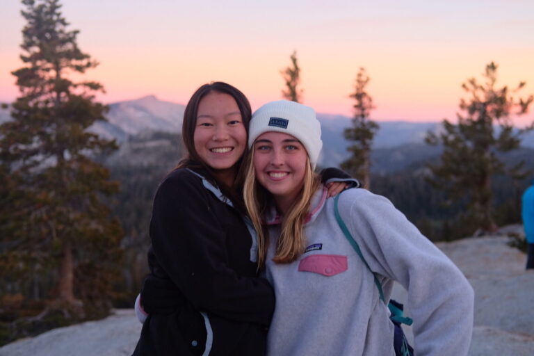 Two girls smiling in front of the sunset