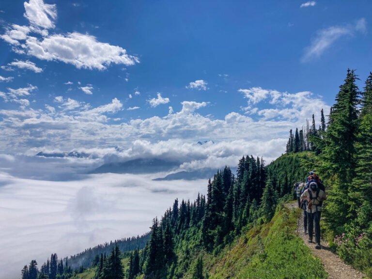 Backpackers on a trail above the clouds