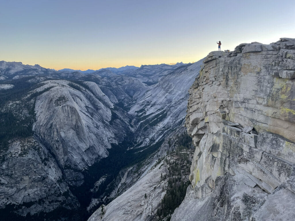 Hiker standing on the edge of Half Dome.