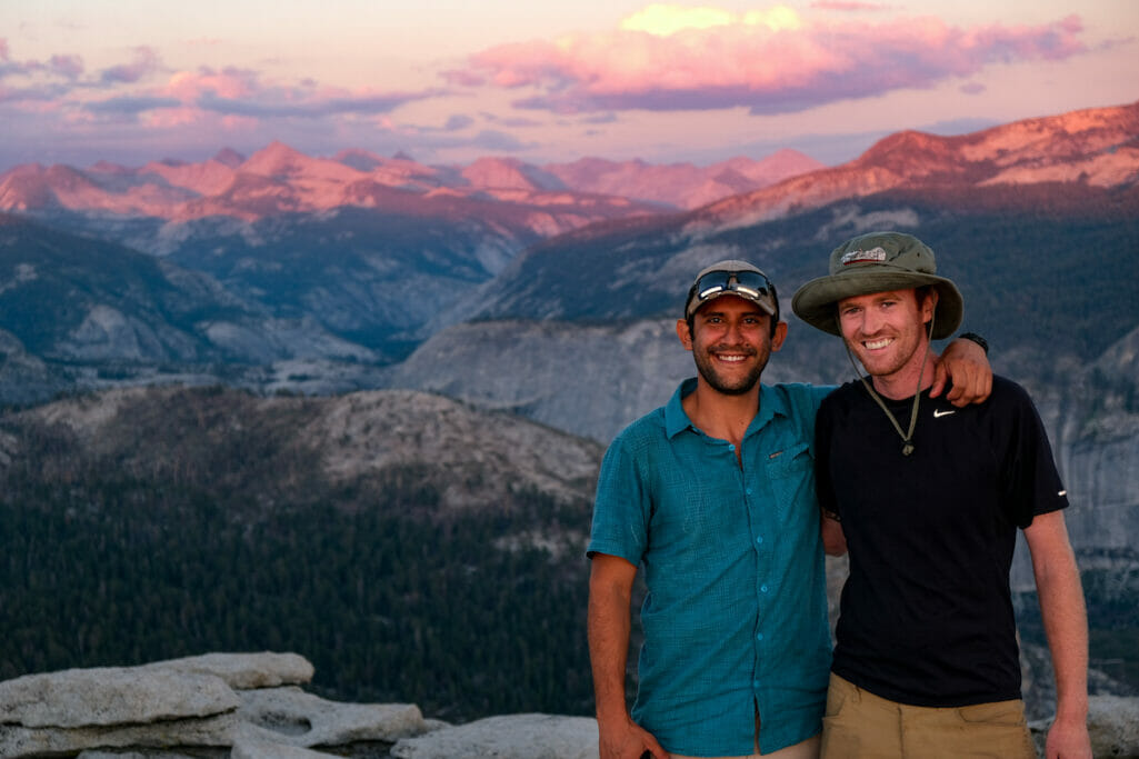 Two guys smile on top of Half Dome for the sunset.