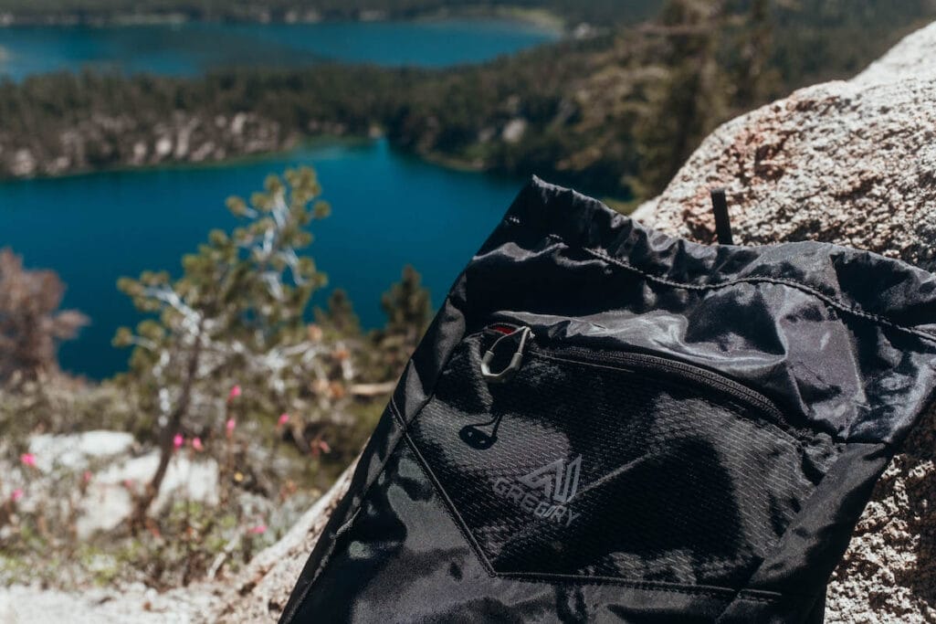 A Gregory backpack sits on a rock in front of a lake.