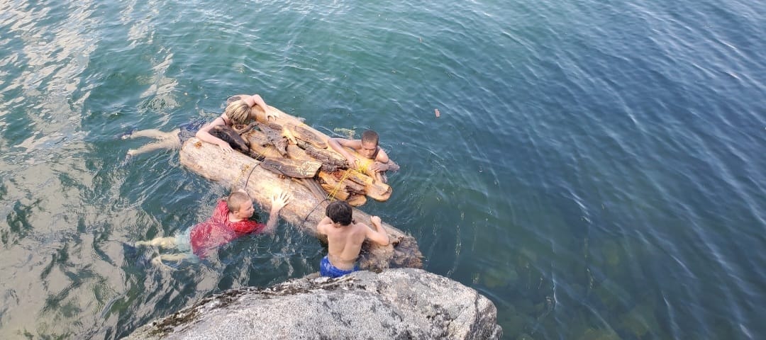 Campers make a raft out of drift wood and float around lake Eleanor. 