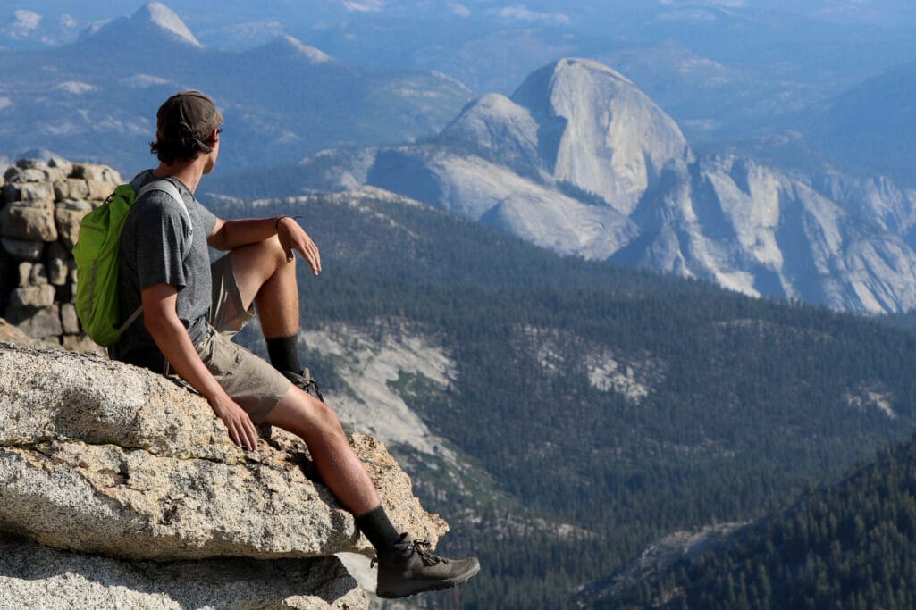 Man relaxing on the summit of Mt Hoffmann with Half Dome in the background.