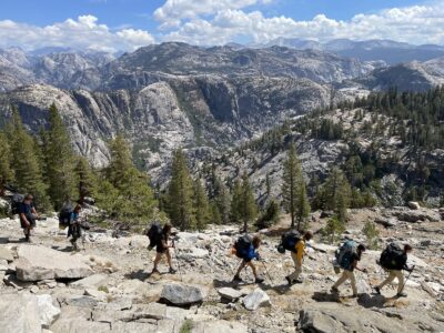 Teens backpacking in Yosemite with an expansive view of the mountains
