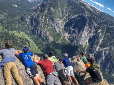 Sitting on the edge of a cliff during a Yosemite summer camp for kids