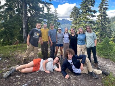 A group of teen backpackers pose in front of a mountain view in Olympic National Park