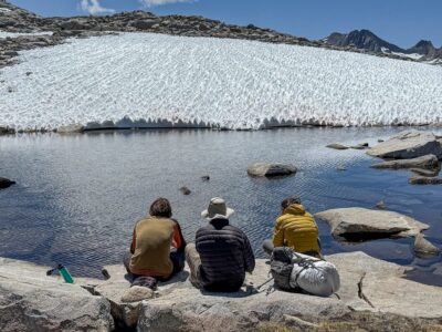 Teens looking at a lake with a snowfield above it